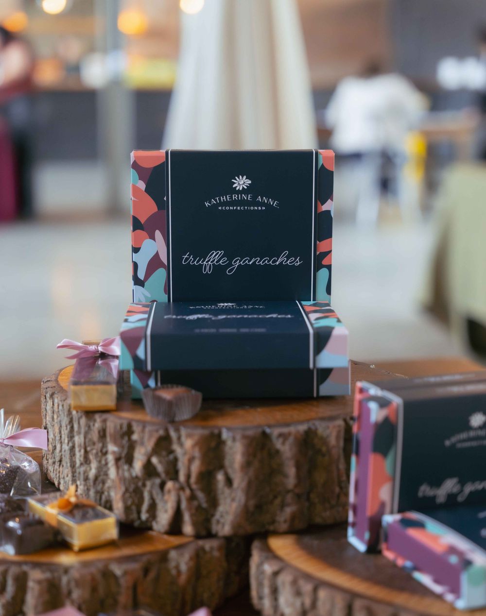Truffle ganaches displayed on rustic wood slices with elegant packaging and branding. By FORGET ME NOT ARTS