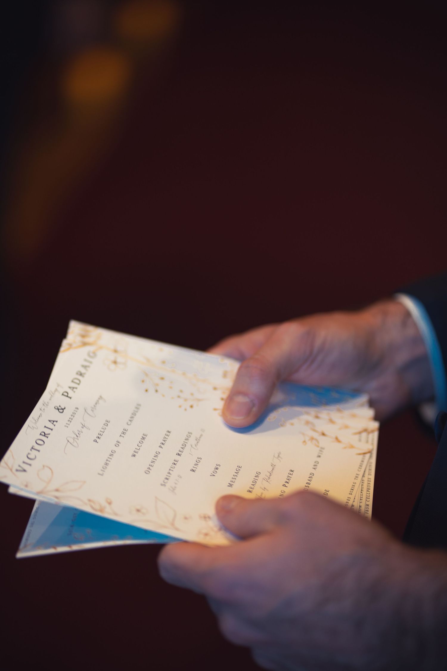 A groomsman's hands holding the wedding program cards