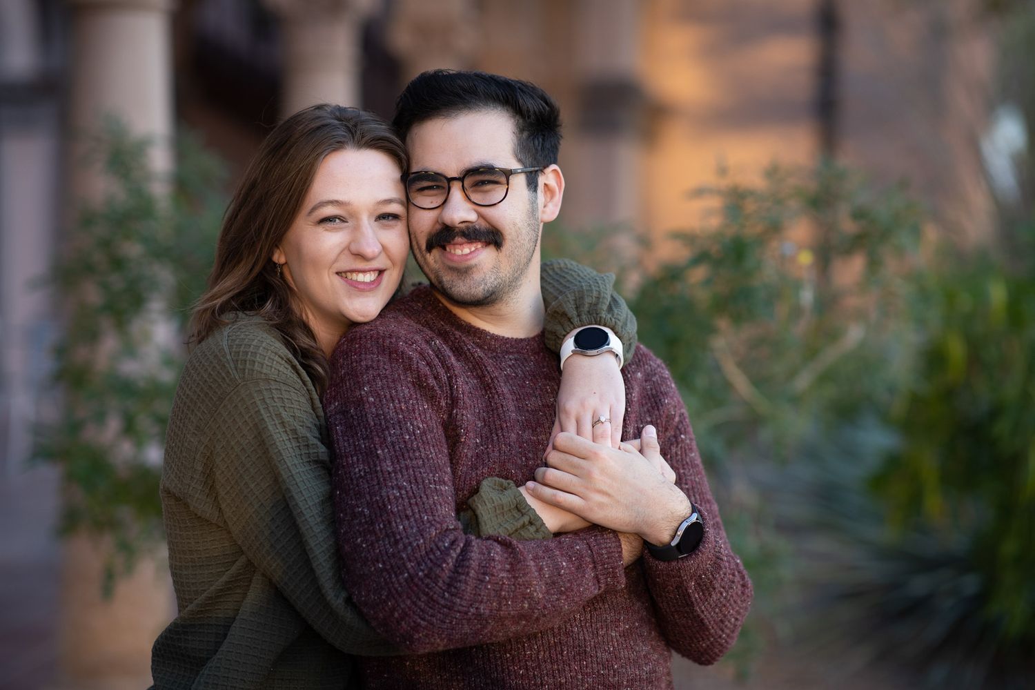 A couple embraces while holding a water bottle in a cozy indoor setting with natural lighting.