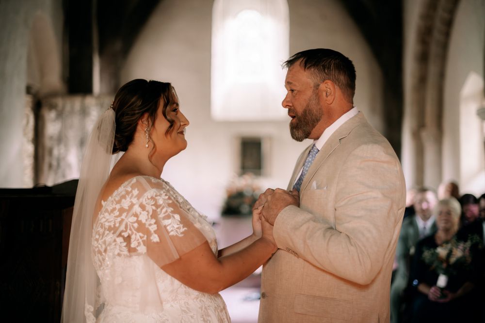A couple shares an emotional first dance moment together in a softly lit church venue during their wedding celebration.