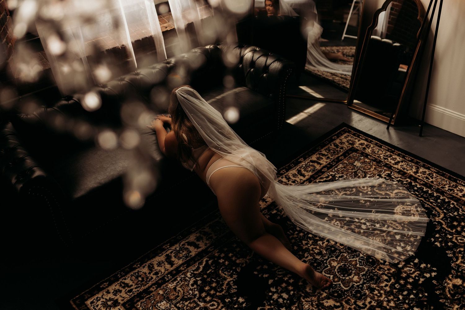 Moody boudoir photograph on a decorative area rug with soft lighting.
