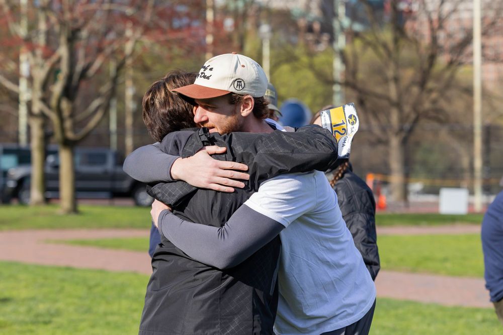 Two people sharing an emotional embrace at an outdoor charity event in a park.