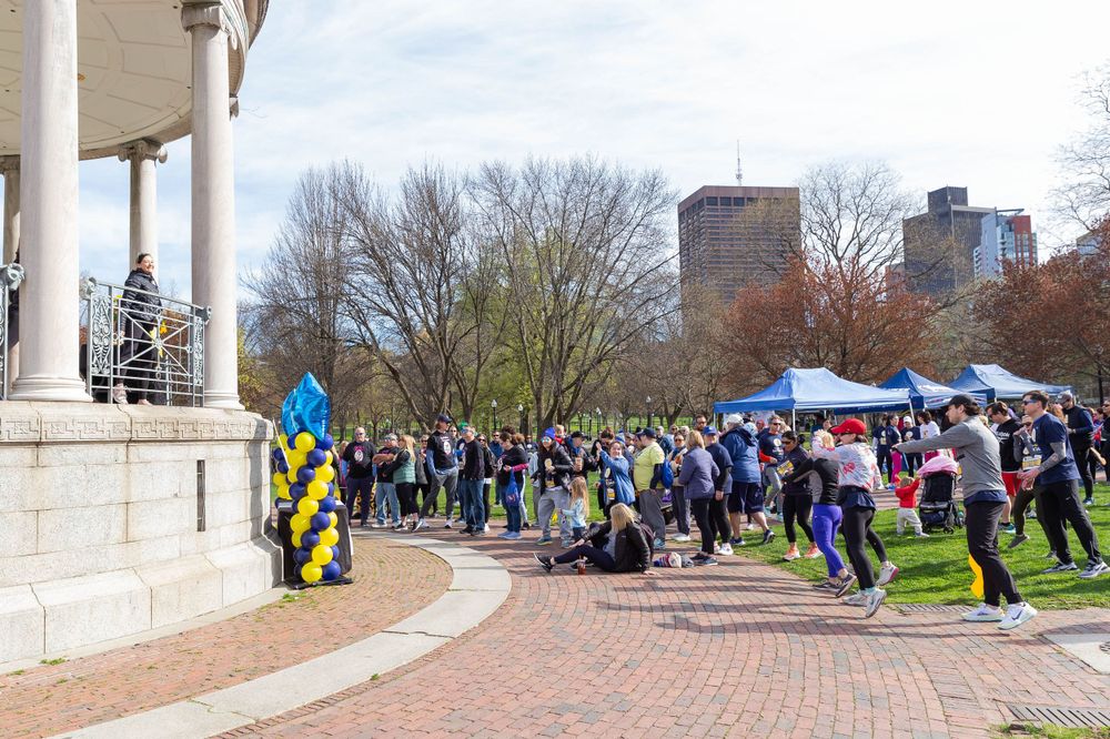 Crowd gathers near gazebo decorated with Ukrainian flag at outdoor community event.