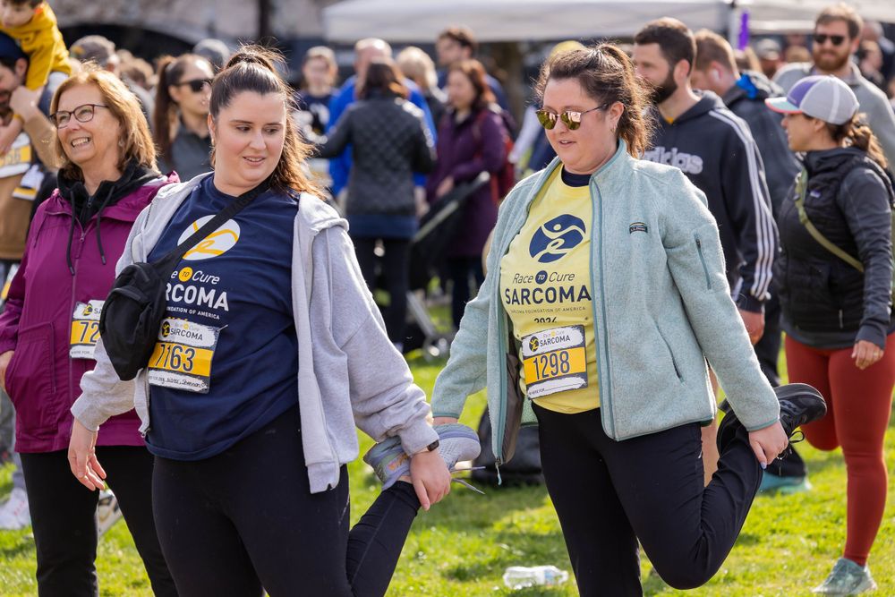 Participants walking together wearing sarcoma awareness shirts at charity event.