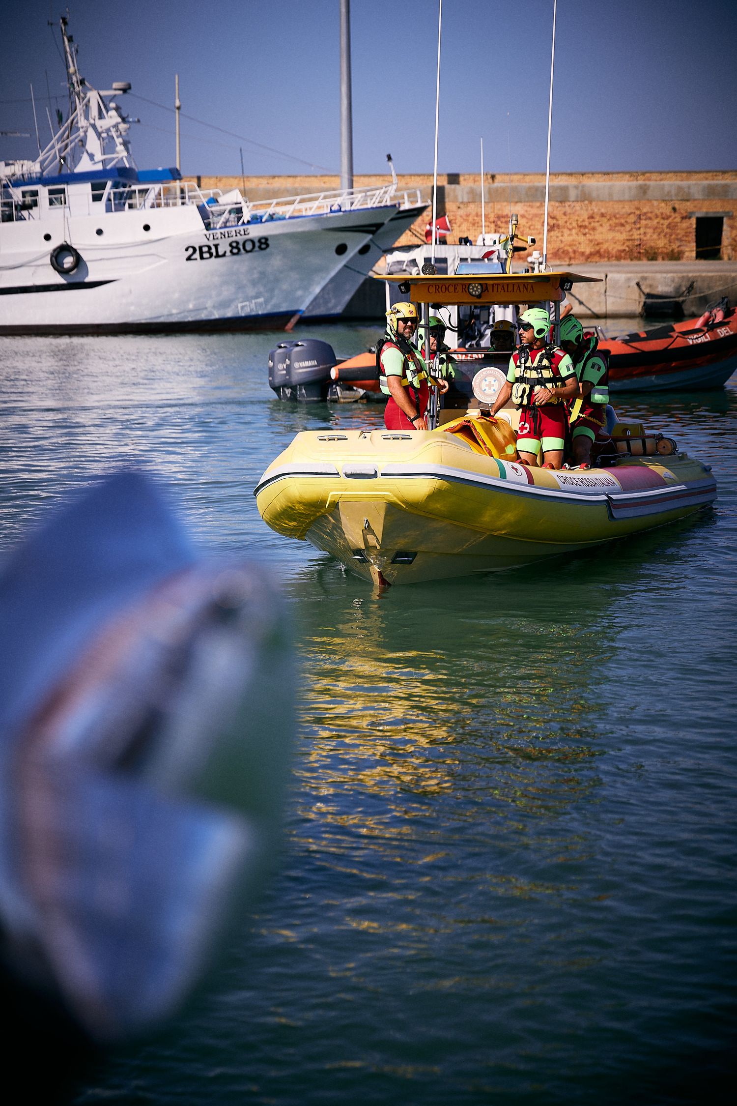 Colorful boats and vessels docked in a marina with clear blue water.