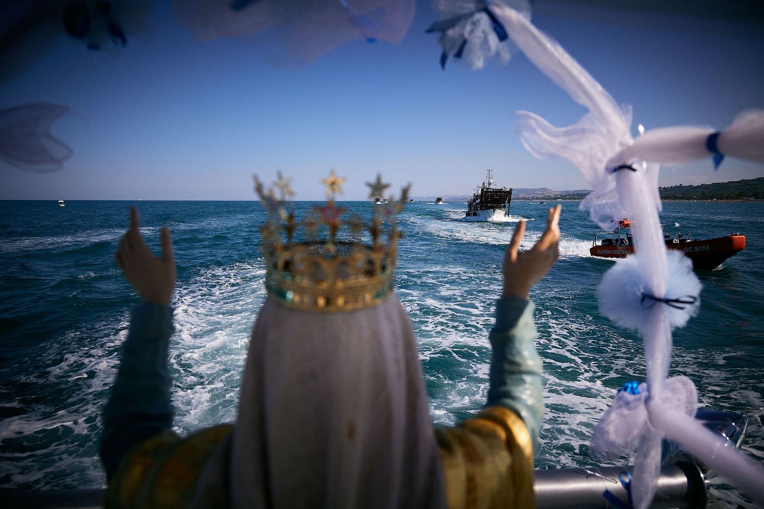 Crown-adorned figure with raised hands among seabirds over ocean waves.