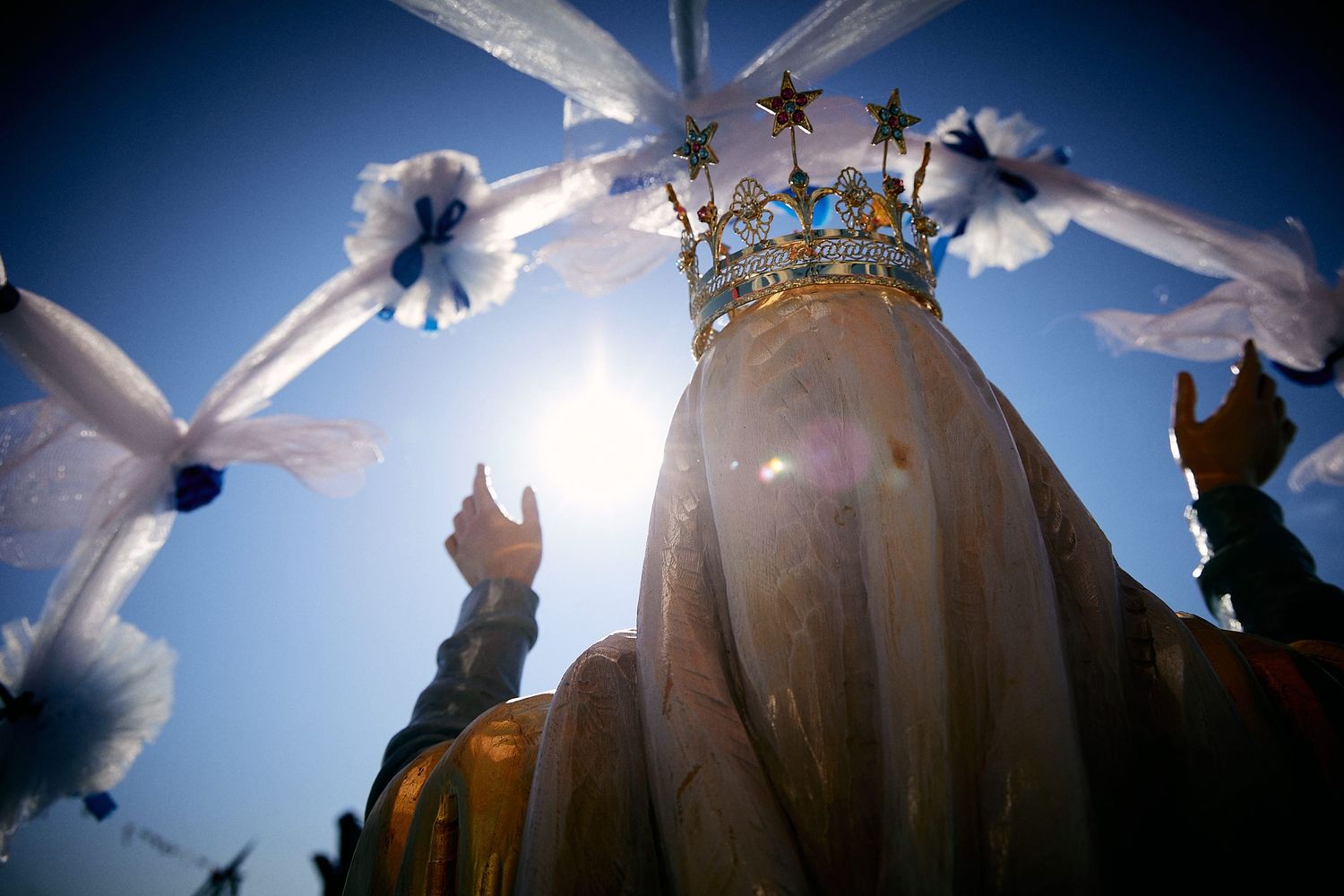 Golden crown against blue sky surrounded by white doves in flight.