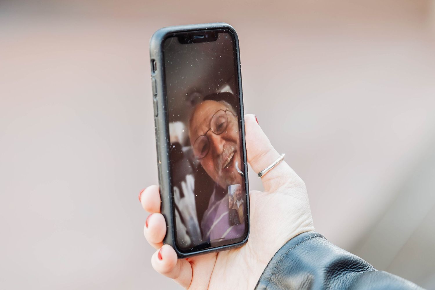 A close-up of a hand holding a smartphone displaying a video call.