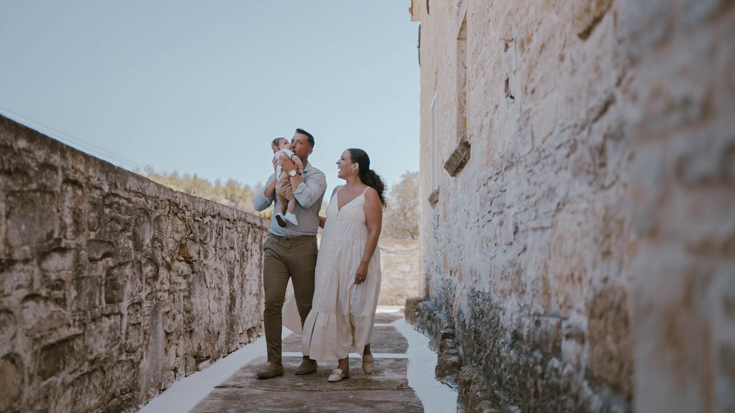 A couple shares a sweet moment while walking along an ancient stone pathway in warm sunlight.
