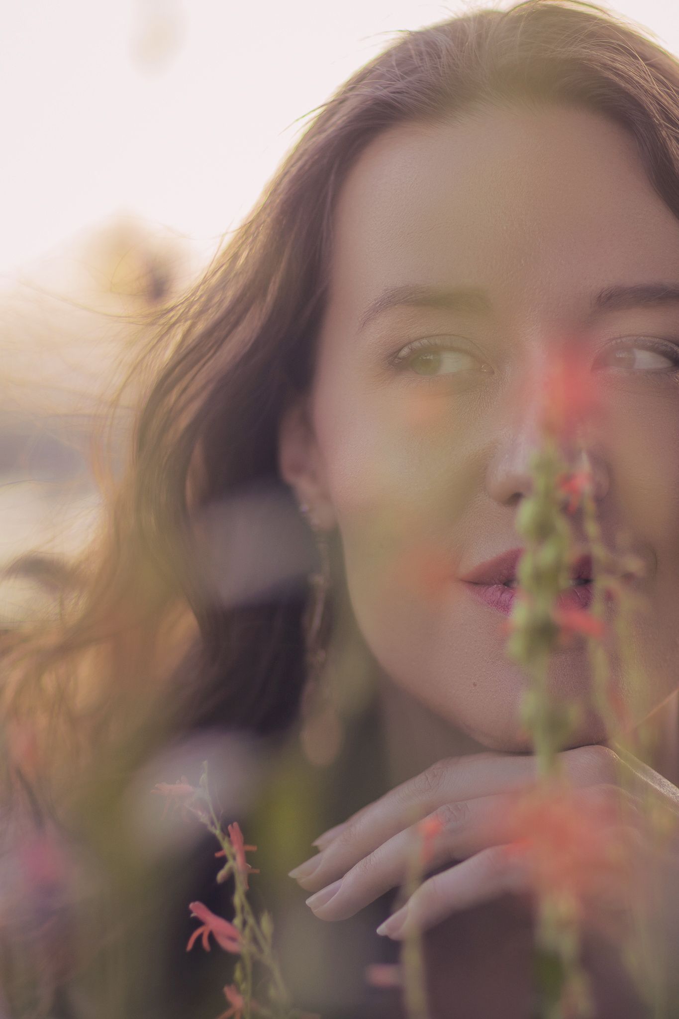 Artistic blurred portrait sequence showing motion of a person smelling a pink flower in soft natural lighting.