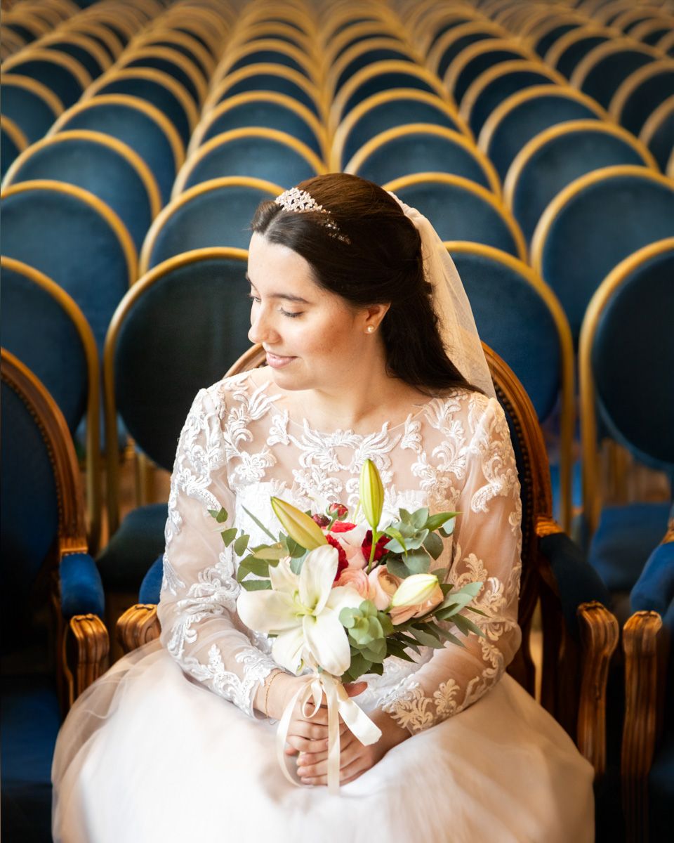 Elegant bridal portrait in a theater with blue velvet seats and ornate gold detailing.
