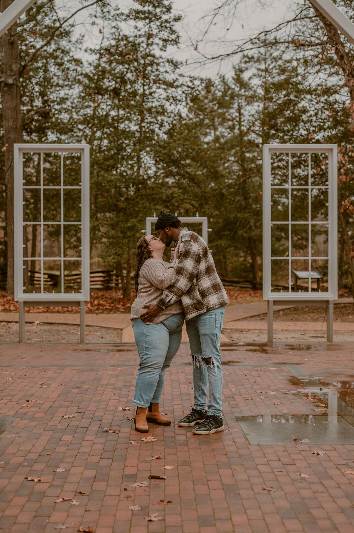 Couple embracing in front of vintage window frames on a brick patio during autumn. photo by Samantha Campbell imagery