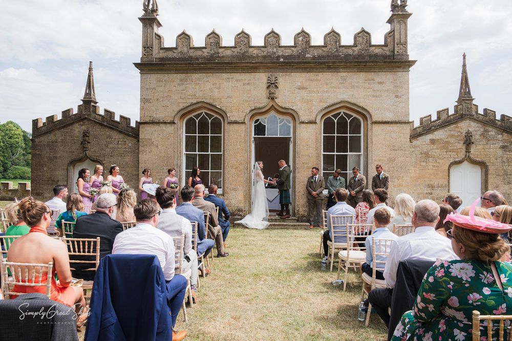 An outdoor wedding ceremony takes place at Fort Henry, a historic Gothic-style church with stone architecture and arched windows.