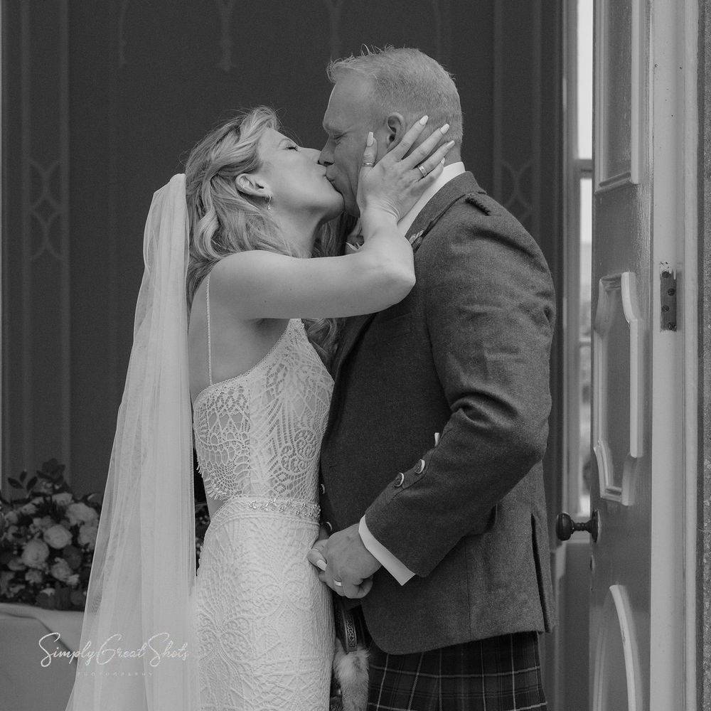 A romantic black & white wedding photo showing a couple sharing a passionate kiss in traditional wedding attire at Fort Henry wedding venue.