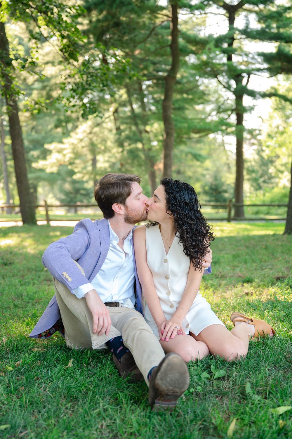 A romantic couple shares a tender kiss while sitting on grass in Central Park on a summer day. Photo by Joliette Marie Photography.