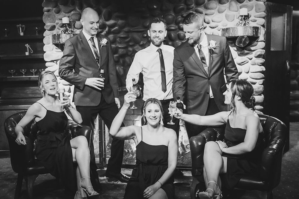 A stylish black and white wedding party photo showing guests and wedding party members posing together.