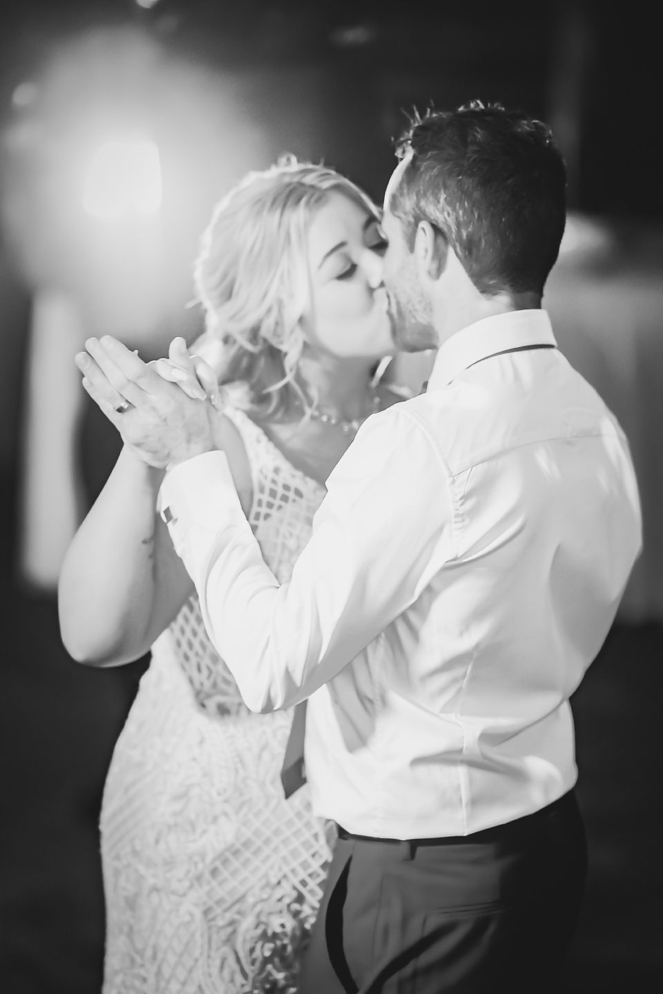 Black and white sequence shows a romantic slow dance with a bride in a lace dress and groom in formal attire.