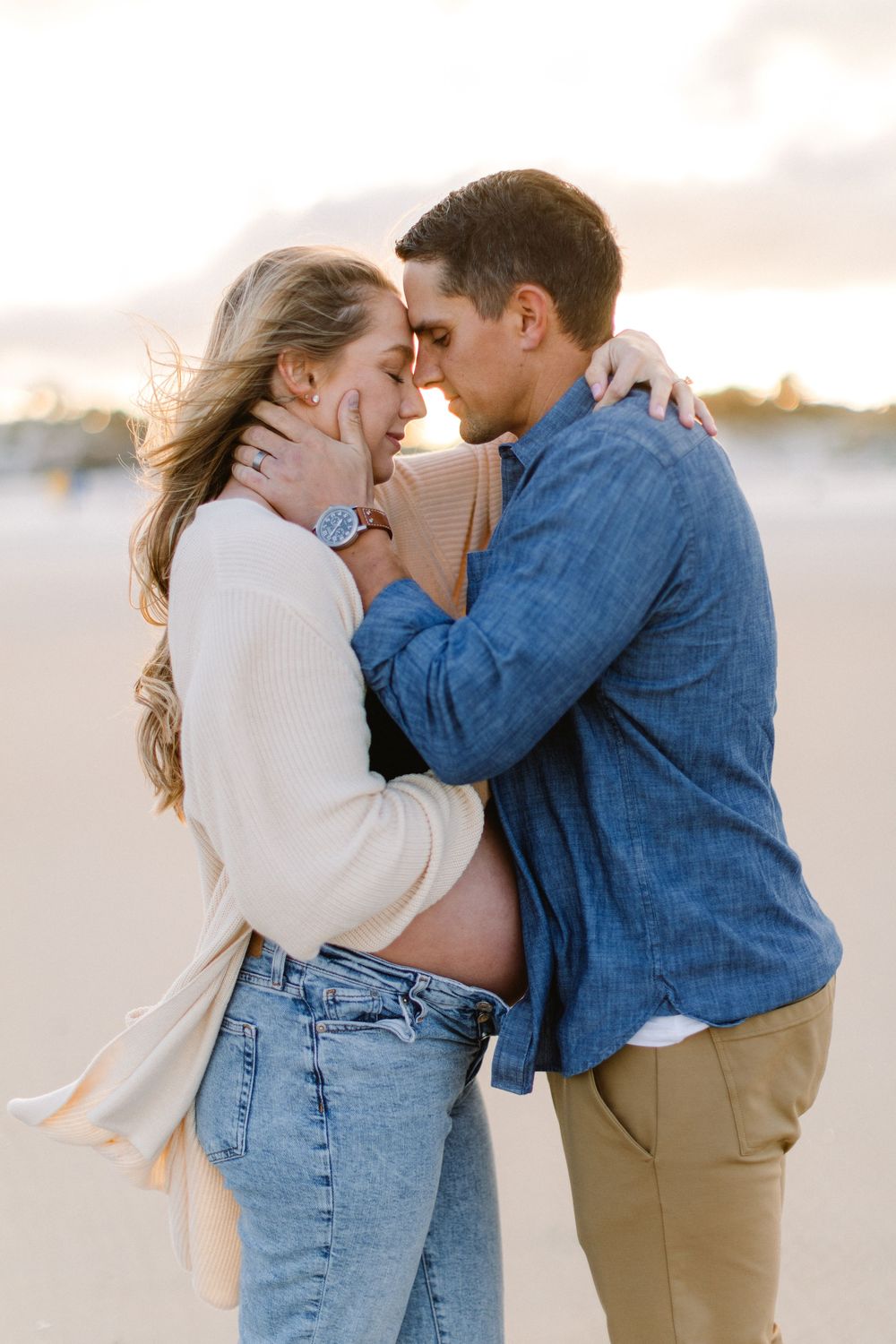 A passionate embrace between a couple on a windswept beach at dusk.