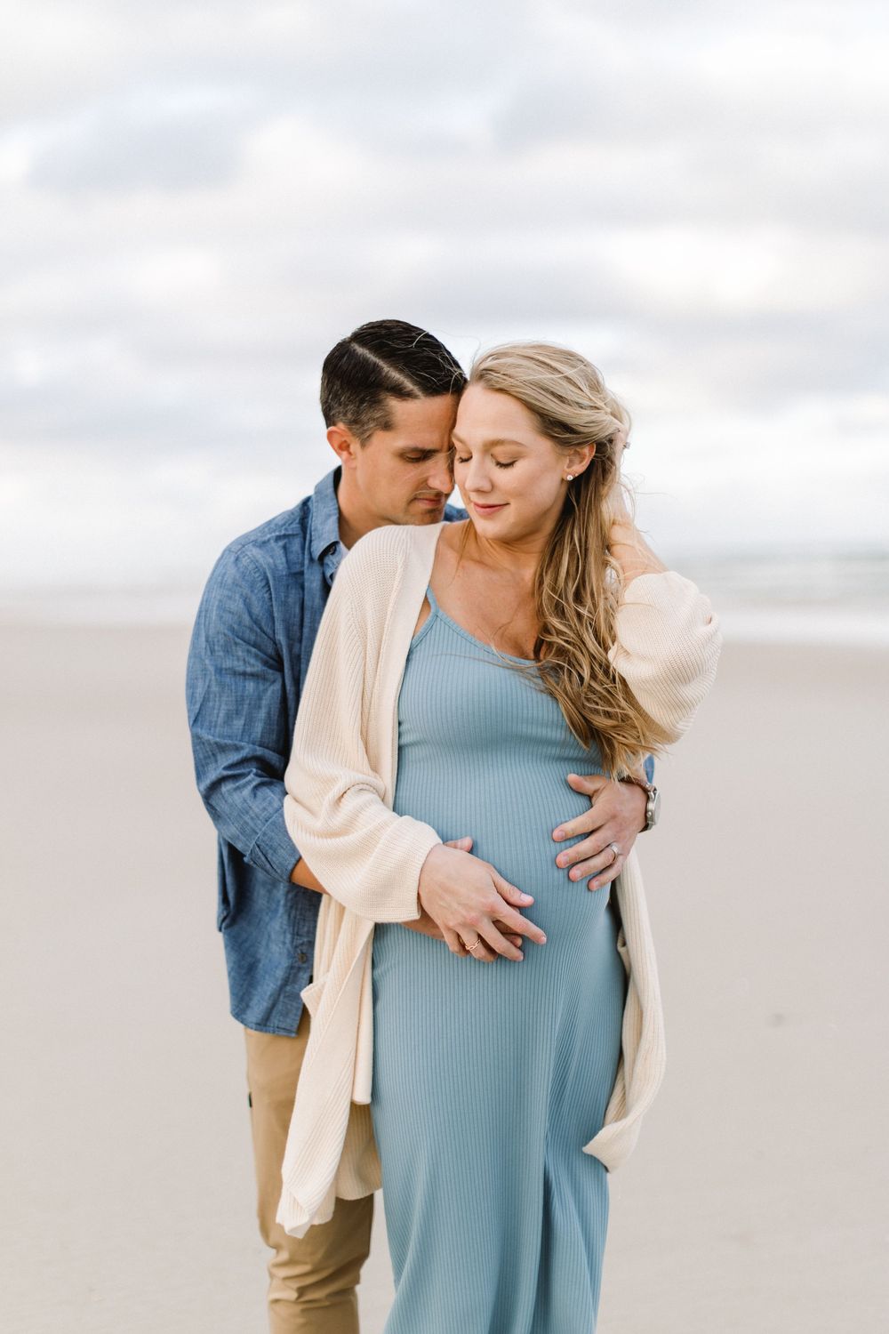 A tender moment between a couple on a beach as they await their new arrival.