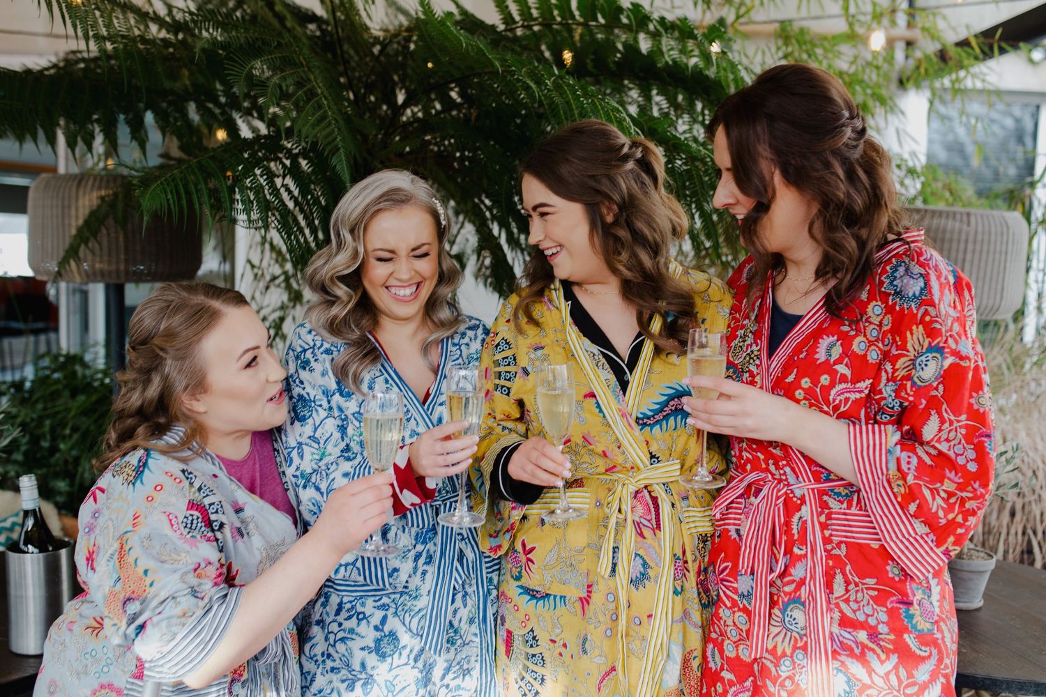 A group in colorful floral robes laugh and smile together during a celebratory gathering.