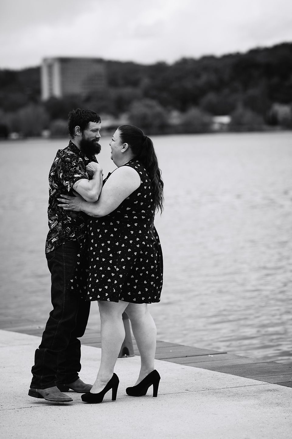 A romantic couple shares tender moments by a lakeside in a series of black and white photographs.