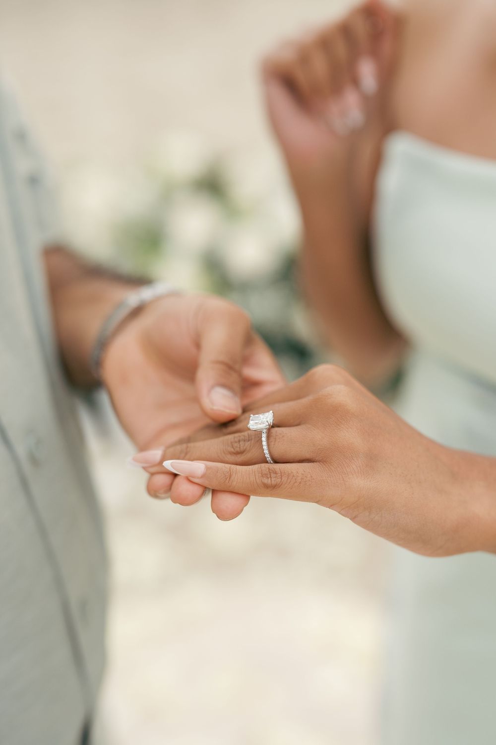 Close-up of hands exchanging wedding rings during marriage ceremony showing elegant diamond engagement ring.