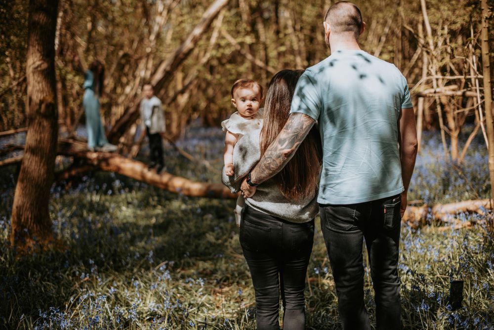 Family enjoys a peaceful moment together while exploring a wooded area with blooming spring flowers.