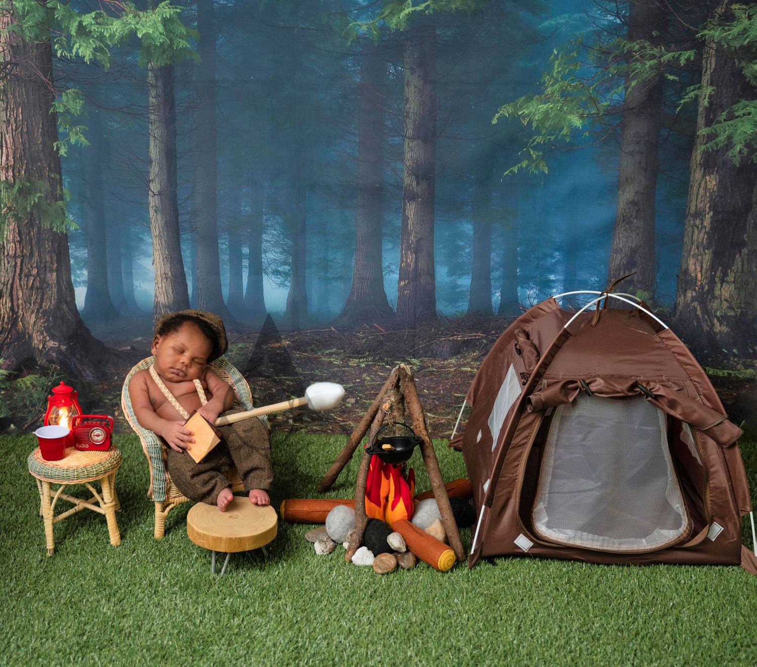 Woodland camping setup with tent, artificial campfire, and forest backdrop.