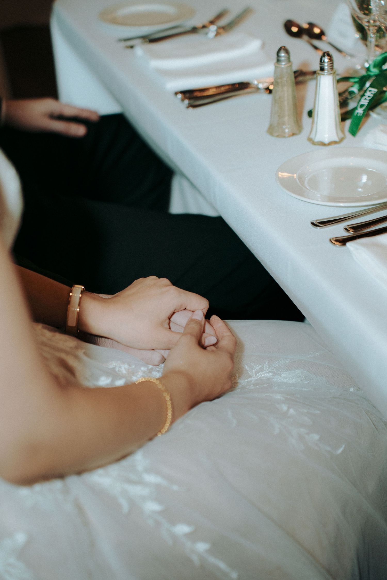 Close-up of wedding table setting with salt and pepper shakers on white tablecloth.