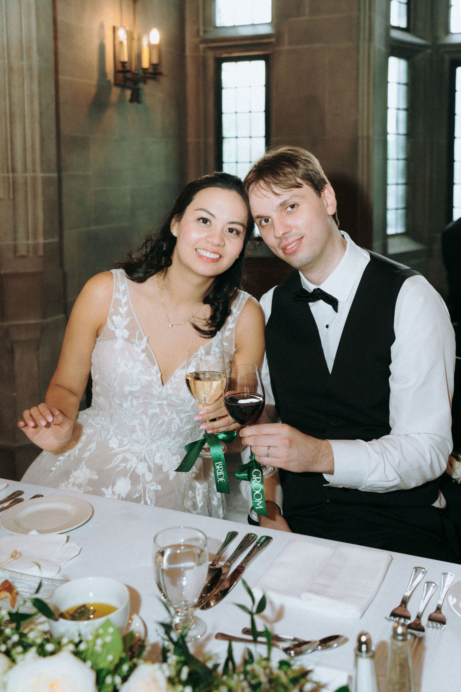 Elegant wedding reception table setting in Gothic architectural interior with candle sconce.