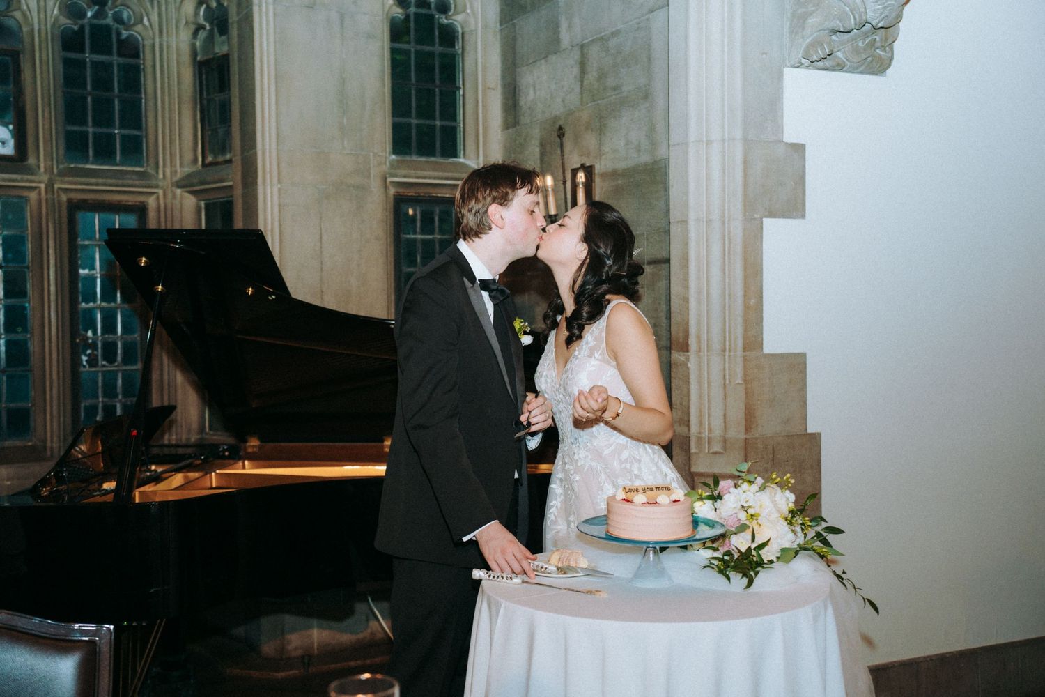 Newlyweds playfully feed each other wedding cake during their reception celebration.