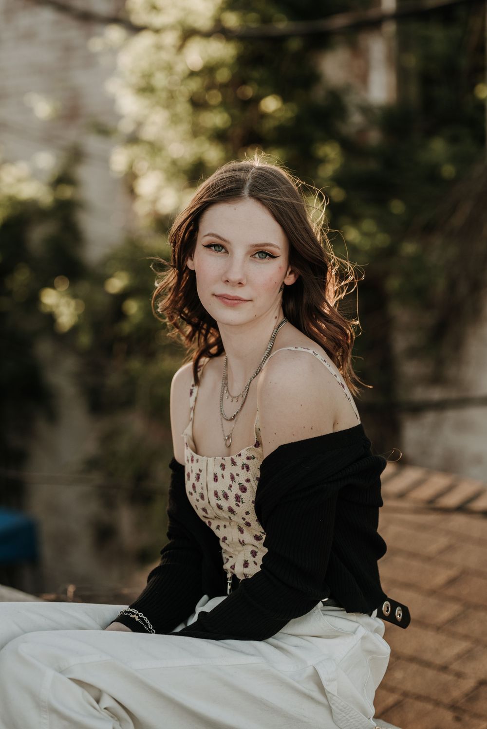 Portrait photograph in natural lighting with soft bokeh background featuring polka dot top and black cardigan at sunset.