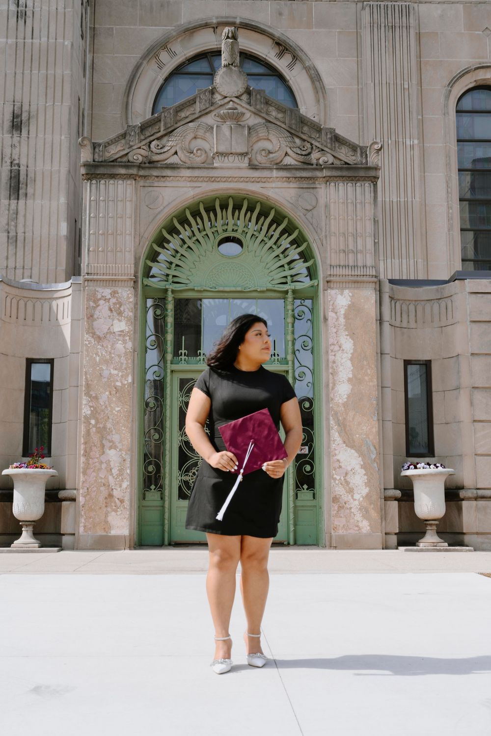 Graduation photo in front of ornate green archway entrance with classical architectural details.