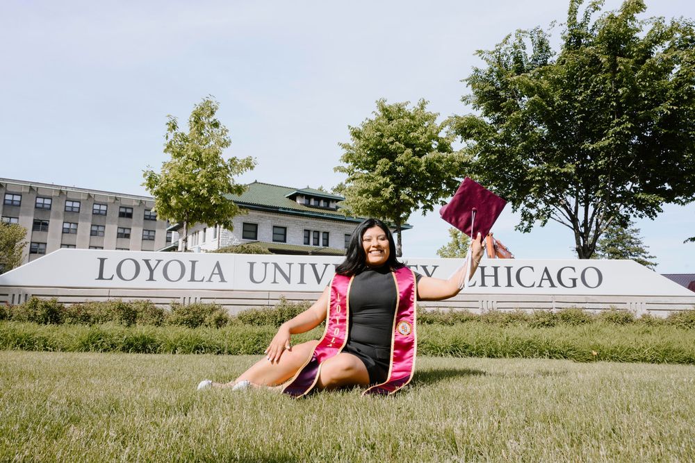 A graduation photo taken on the lawn in front of the Loyola University Chicago sign during commencement season.