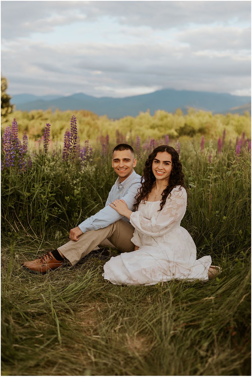 A NH couple taking engagement pictures in a field of purple lupine photos