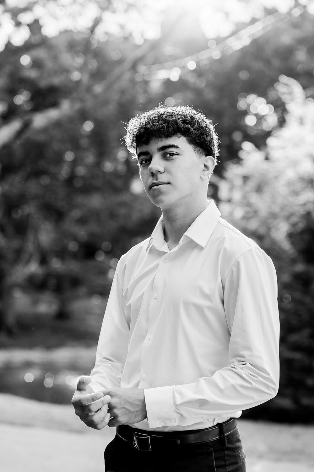 Black and white portrait photo of someone in a white dress shirt outdoors with blurred bokeh background.