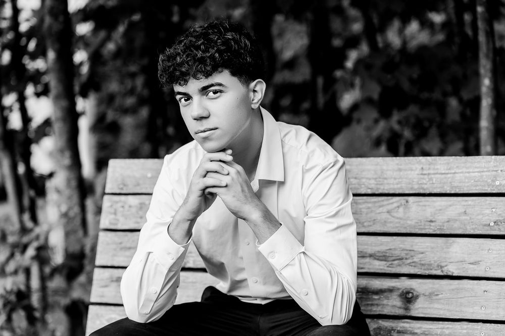A vintage black and white photo of someone sitting on a wooden bench in a meditative pose.