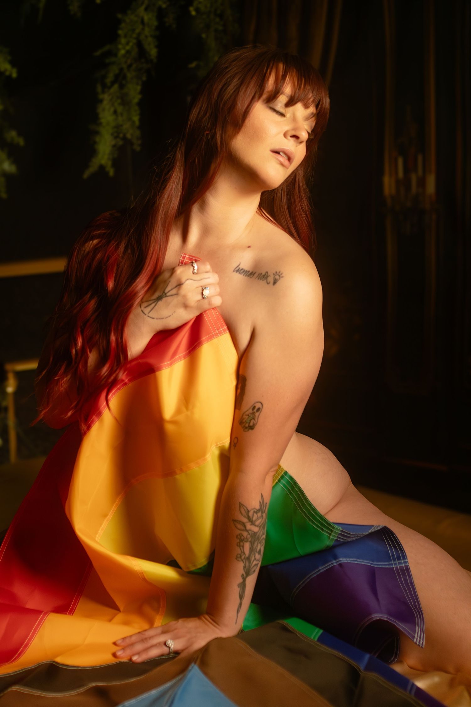 Person kneeling in Progress Pride flag during an inclusive boudoir photography session at Lock and Key Photography in Fort Worth, TX.