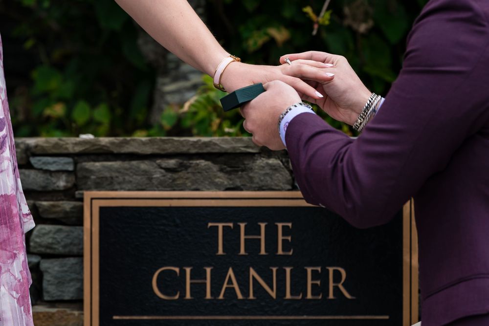 Two people hold hands next to a wooden sign reading 'The Chanler' in copper-colored lettering.