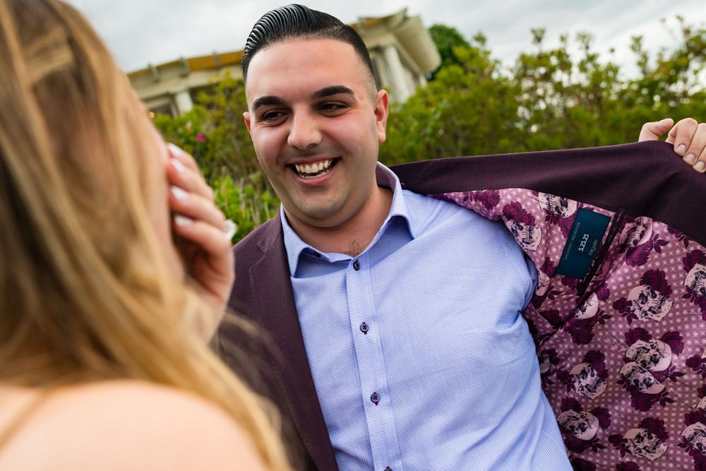 A person and their companion share candid moments during an outdoor portrait session in a garden setting.