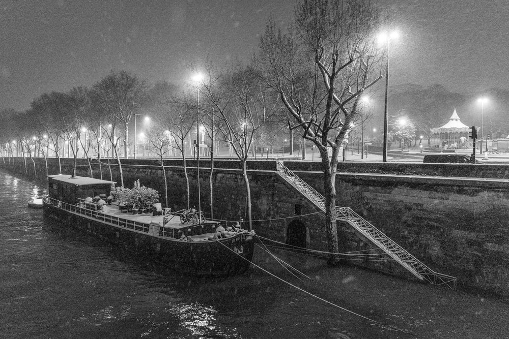 A series of black and white nighttime photographs showing lamp posts illuminating a misty urban canal pathway.
