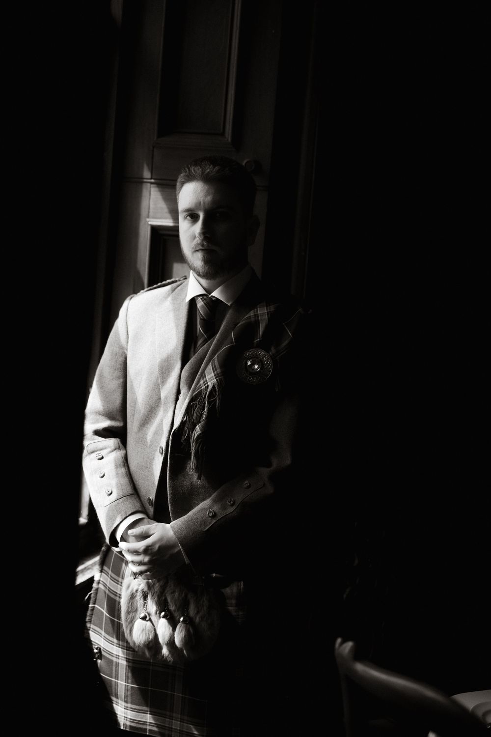 A black and white portrait series showing someone in formal attire with dramatic lighting and shadows.