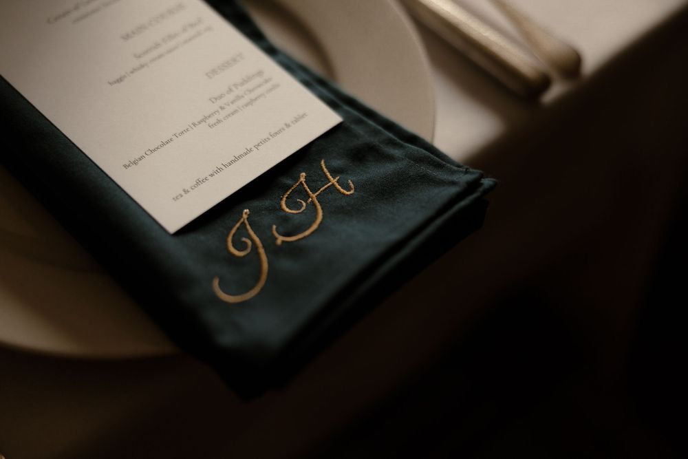 Gold monogram initials elegantly embroidered on a navy blue fabric against a soft neutral background.