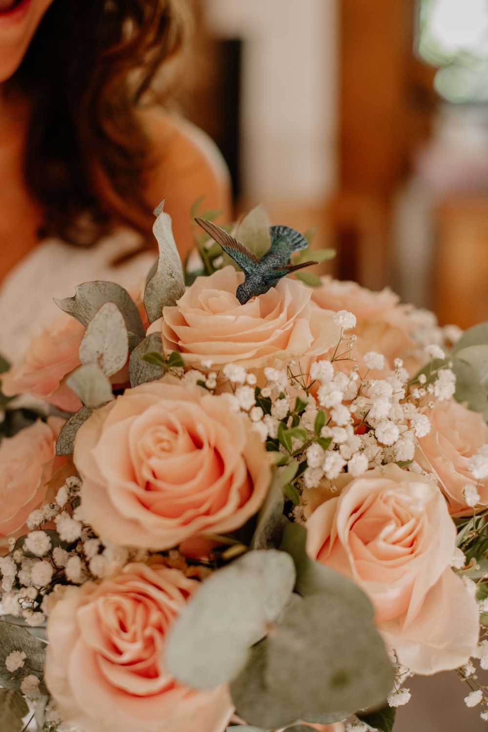 Romantic peach roses arranged with eucalyptus leaves and delicate baby's breath in soft focus floral bouquet.