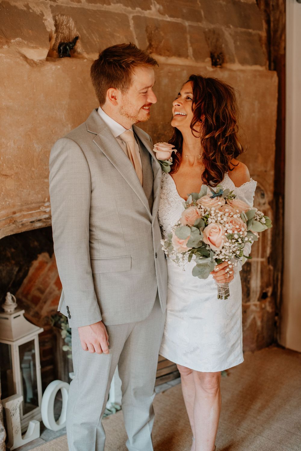 A loving couple shares a joyful moment at their intimate wedding, bride holding a blush pink bouquet.