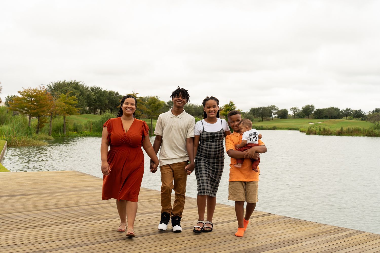 A happy group strolls together on a wooden dock overlooking a serene lake.