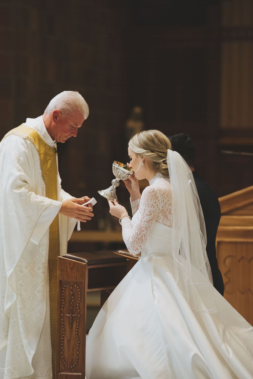 A religious ceremony shows a traditional Catholic communion ritual at a wedding in a church.