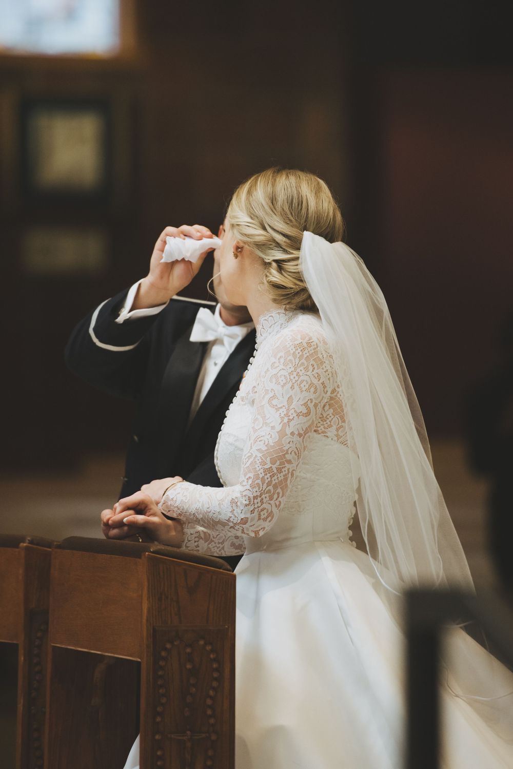 A groom wipes away a tear drop from his bride during their wedding ceremony.
