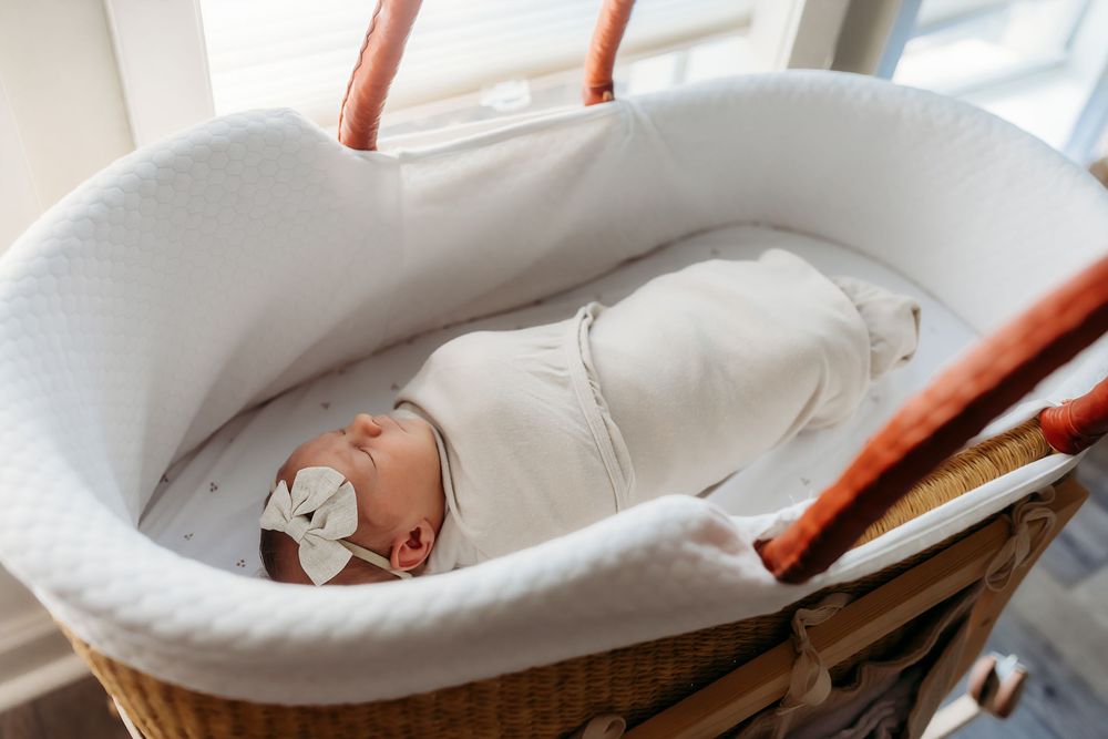 A sequence of photos showing a baby being gently swaddled in a soft white blanket with delicate dot pattern details.