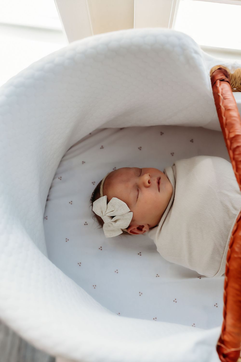 Progressive shots demonstrating swaddling technique with a white dotted blanket in a cozy nursery setting.